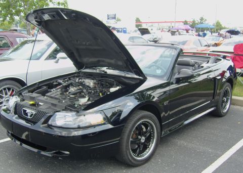 2007 Ford Mustang - A black convertible Mustang is parked with its hood open, revealing the engine bay.
