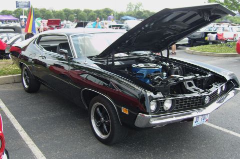 2007 Ford Mustang - A black 1970 Ford Torino GT is parked with its hood open, revealing the engine bay at an outdoor car show.