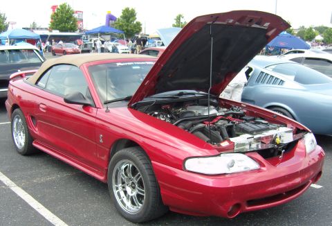 2007 Ford Mustang - A red convertible Mustang from the 1994-1998 generation is displayed with its hood open at a car show.