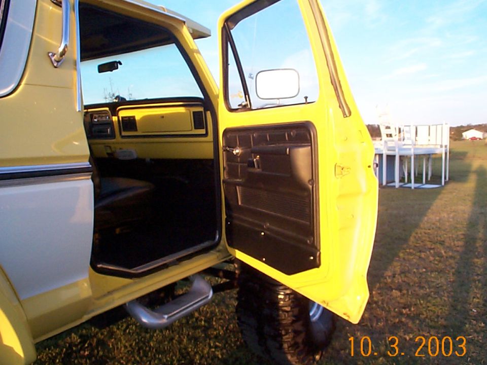 Open yellow passenger door showing brown interior door panel, dash and chrome step on lifted truck