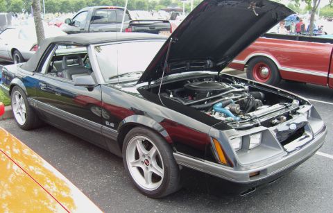 2007 Ford Mustang - Convertible Mustang with engine exposed, parked next to a red truck.