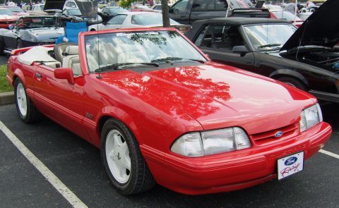 2007 Ford Mustang - A red convertible with a white interior is parked at an outdoor event, with other vehicles in the background.