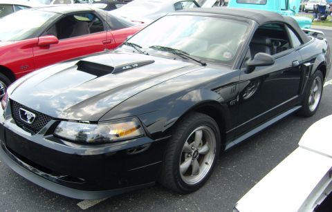 2007 Ford Mustang - Black 2007 Ford Mustang convertible parked next to a red car.
