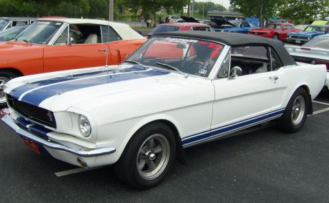 2007 Ford Mustang - White 1965 Ford Mustang convertible with blue racing stripes parked at an outdoor event.