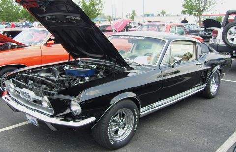 2007 Ford Mustang - A black 1967 Ford Mustang is displayed with its hood open, parked in a lot with other vehicles.