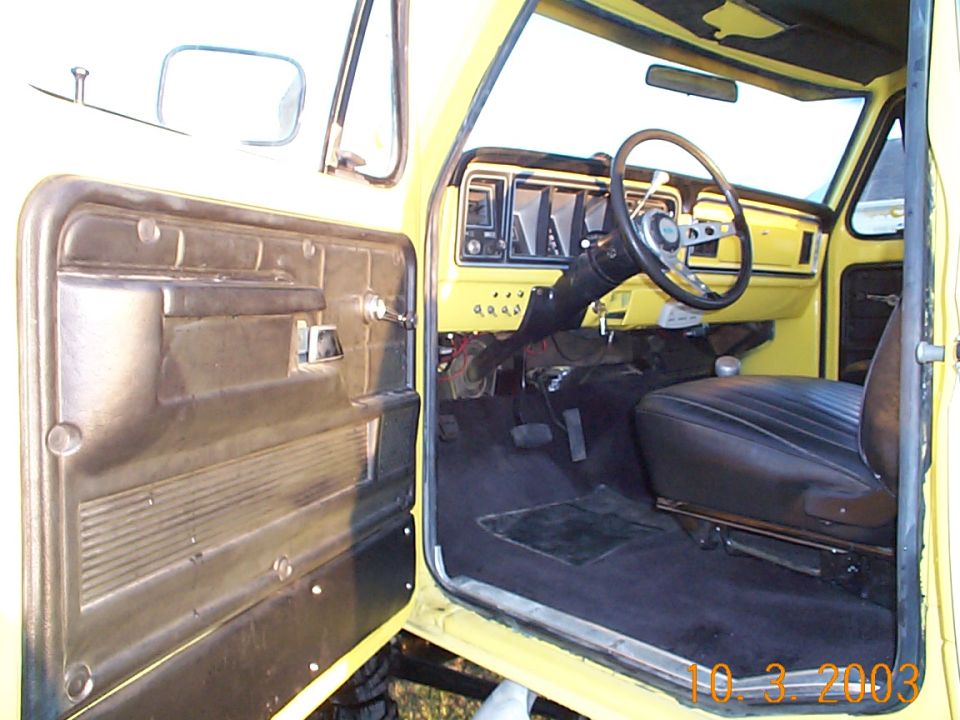 Yellow truck interior, showing the driver's side door open, dashboard, steering wheel, and seat