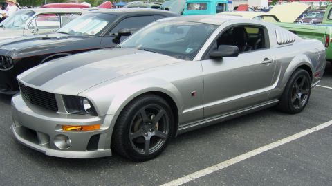 2007 Ford Mustang - A silver Ford Mustang is parked at an outdoor event, with other cars visible in the background.