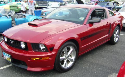 2007 Ford Mustang - A red Ford Mustang GT is shown from a three-quarter front view at an outdoor car show.