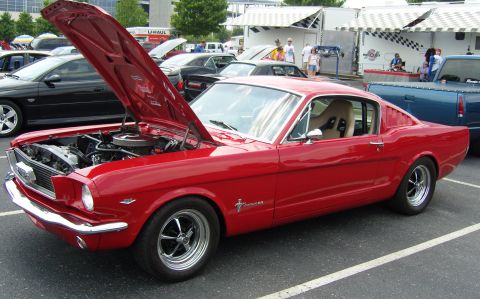 2007 Ford Mustang - A red classic Ford Mustang is parked with its hood open, showing the engine bay.