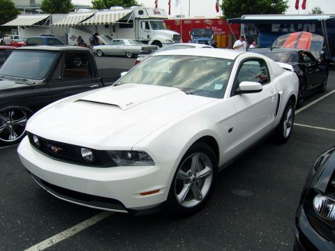 2007 Ford Mustang - White 2007 Ford Mustang with a prominent hood scoop is parked at an outdoor event.