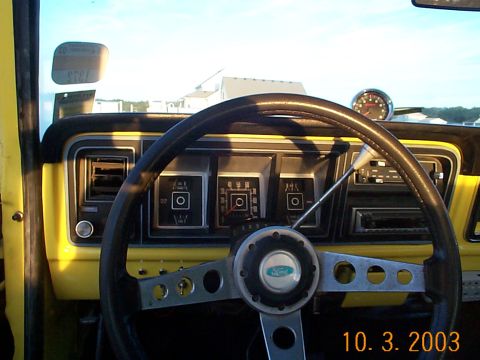 1978 Ford Bronco - The interior of a yellow 1978 Ford Bronco shows a black steering wheel and dashboard with various gauges and controls.