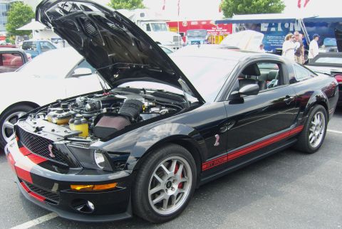 2007 Ford Mustang - A black 2007 Ford Mustang GT500 is displayed with its hood open, revealing the engine and red racing stripes.
