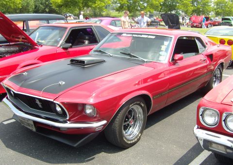 2007 Ford Mustang - A red 1969 Ford Mustang Mach 1 is parked at a car show, with other vehicles visible.
