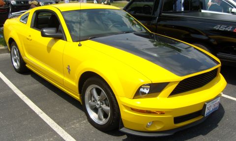 2007 Ford Mustang - Yellow 2007 Ford Mustang coupe parked in a lot, showing its front 3/4 view.