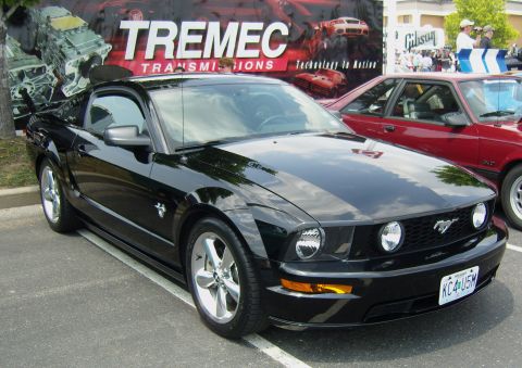 2007 Ford Mustang - A black 2007 Ford Mustang is parked in a lot with a Tremec Transmissions banner in the background.