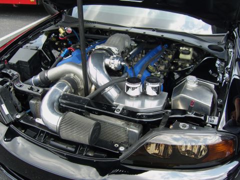 2007 Ford Mustang - Engine bay view of a modified V8 with turbocharger and custom intake system.