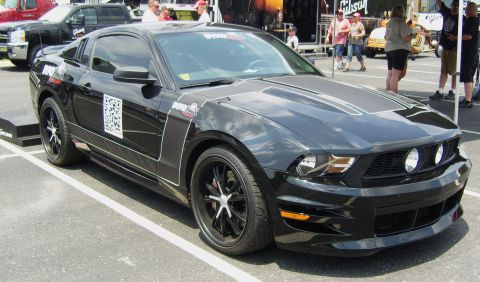 2007 Ford Mustang - A black Ford Mustang is parked at an outdoor event, with people and other vehicles in the background.