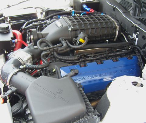 2007 Ford Mustang - Close-up of a supercharged engine bay, blue "Powered by Ford" valve covers and a prominent black supercharger.
