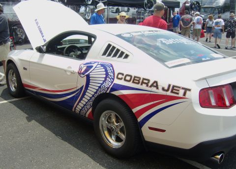 2007 Ford Mustang - A white Ford Mustang with custom Cobra Jet graphics and racing wheels is displayed with its hood open.