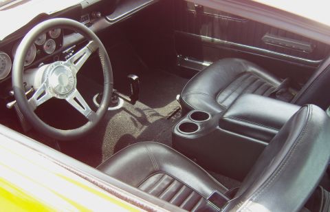2007 Ford Mustang - The interior of a classic car features black leather seats and a custom steering wheel.
