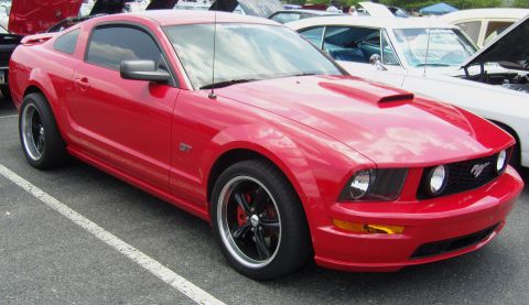 2007 Ford Mustang - A red Ford Mustang GT is parked at an outdoor event, with other vehicles visible in the background.