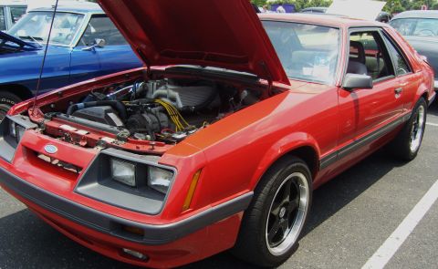 2007 Ford Mustang - A red 1987 Ford Mustang coupe is displayed with its hood open, revealing the engine bay. Another vehicle is visible to the left.