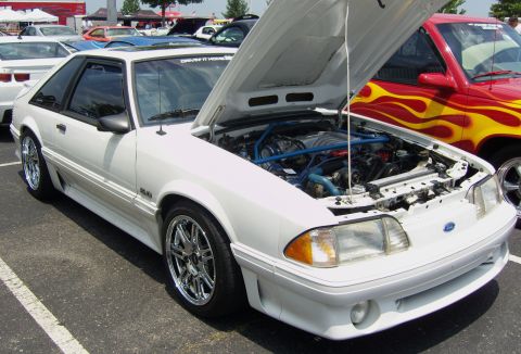 2007 Ford Mustang - A white Ford Mustang, likely from the late 1980s, is parked with its hood open, revealing the engine bay.