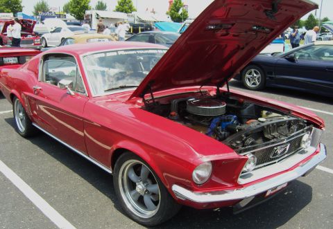 2007 Ford Mustang - A red classic Ford Mustang is displayed with its hood open, revealing the engine bay.