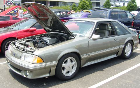 2007 Ford Mustang - A gray Ford Mustang GT from the late 1980s or early 1990s is displayed with its hood open at a car show.