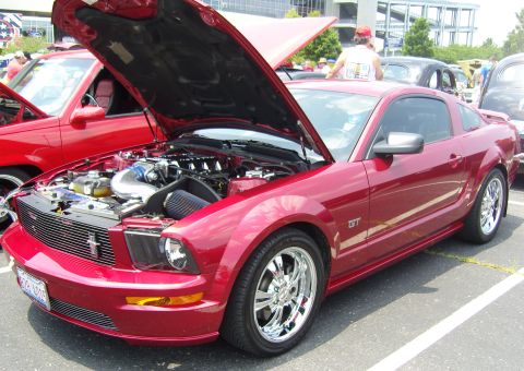 2007 Ford Mustang - A red Ford Mustang GT is parked with its hood open, revealing the engine bay.