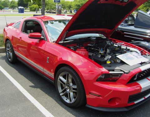 2007 Ford Mustang - A red 2007 Ford Mustang GT500 is displayed with its hood open, revealing the engine and GT500 badging on the fender.
