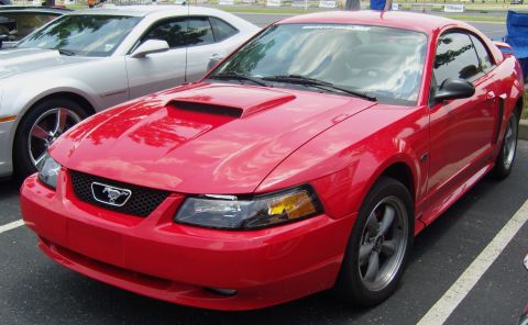 2007 Ford Mustang - A red Ford Mustang is parked at an event, with another car visible beside it.