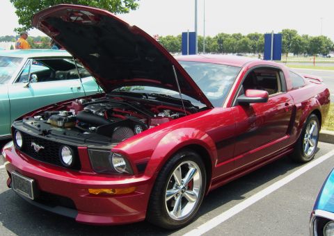 2007 Ford Mustang - Red 2007 Ford Mustang on display with its hood raised, revealing the engine compartment.