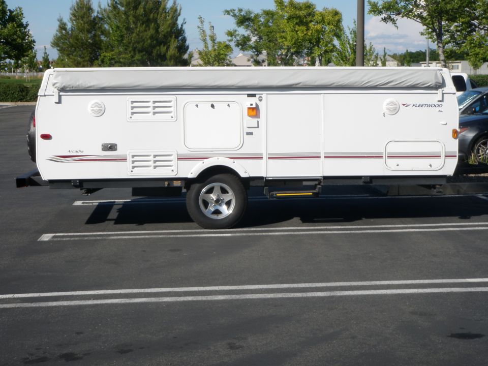 White Fleetwood pop-up camper trailer, side view, parked in lot