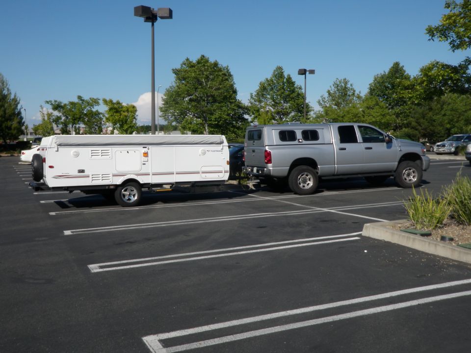 Silver 2007 Dodge 2500 pickup truck with a camper shell towing a white pop-up trailer