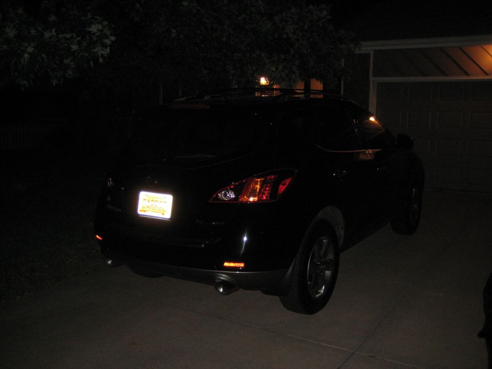 Black SUV's rear view at night with illuminated license plate