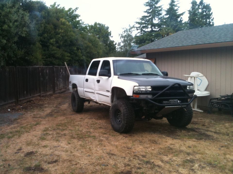 White lifted Chevrolet crew cab pickup with prerunner bumper in yard