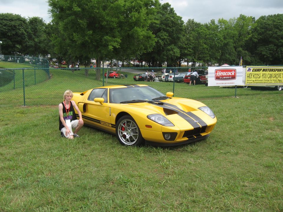 Yellow Ford GT with black racing stripes parked on grass