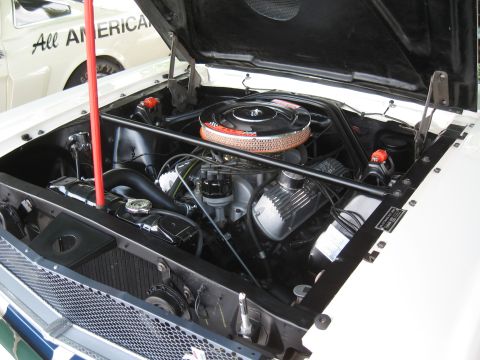 1968 Shelby GT500 - The engine bay of a 1968 Shelby GT500 is visible, with another car bearing "All AMERICAN" text in the background.