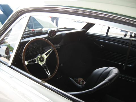 1968 Shelby GT500 - The interior of a classic Mustang features a wood-rimmed steering wheel, racing seat, and a visible number 70 on the window.