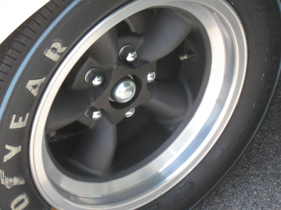 Close-up of a black five-spoke wheel with a polished lip and a Goodyear tire. Some text is visible on the tire sidewall