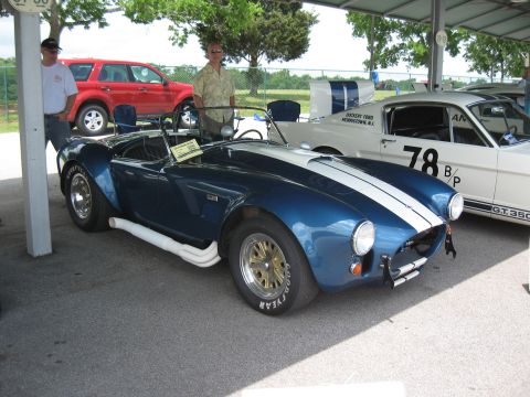 1968 Shelby GT500 - A blue AC Cobra with white racing stripes is parked next to a white Ford Mustang.