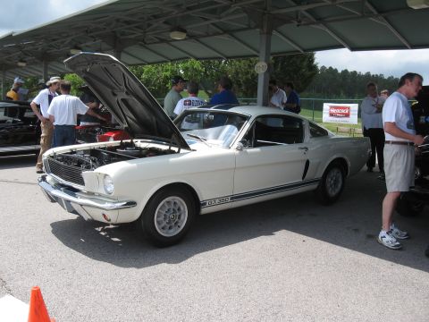 1968 Shelby GT500 - A white 1966 Ford Mustang coupe is displayed with its hood open at an outdoor event.