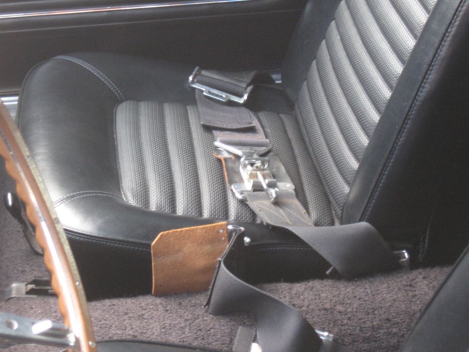 Interior view of a car seat with seatbelt and part of a steering wheel