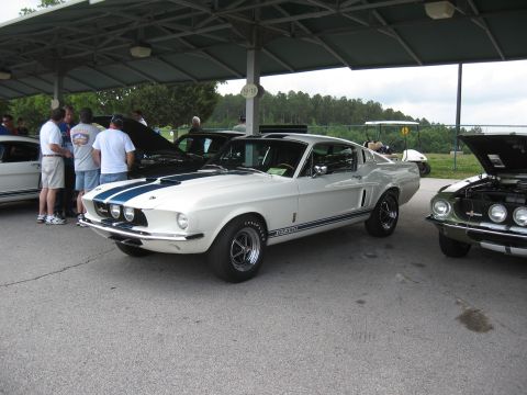 1968 Shelby GT500 - White 1968 Shelby GT500 with blue stripes is displayed at an outdoor event with other vehicles.