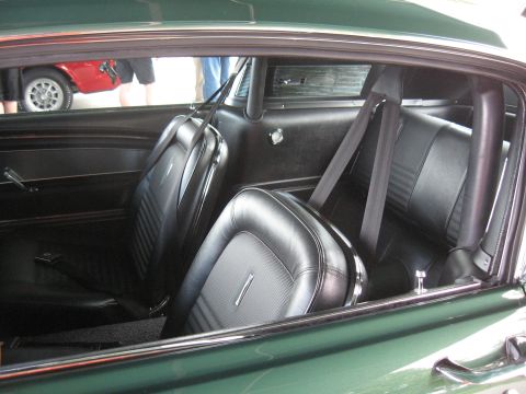 1968 Shelby GT500 - The interior of a vintage car, black bucket seats and seatbelts, with another vehicle visible through the window.