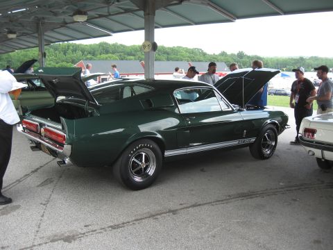 1968 Shelby GT500 - A dark green 1968 Shelby GT500 is displayed with its hood and trunk open at an outdoor event.