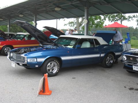 1968 Shelby GT500 - A blue 1969 Mustang convertible is displayed with its hood and trunk open, alongside other vehicles.