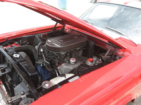 1968 Shelby GT500 - The engine bay of a red 1968 Shelby GT500 is visible with the hood open.
