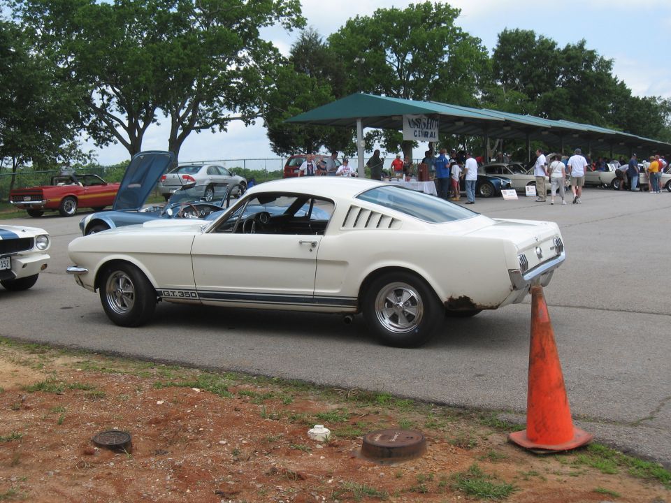 White 1965-1966 Ford Mustang fastback with GT350 side stripe parked at an outdoor event